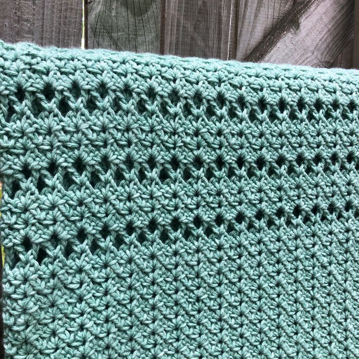 a green crocheted blanket sitting on top of a wooden table