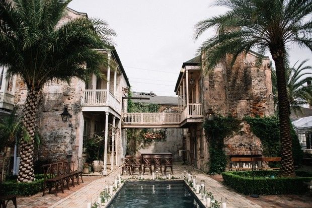 an outdoor pool surrounded by palm trees next to two story buildings with balconies