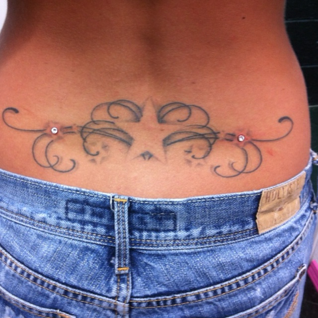 a woman's stomach with an intricate tattoo on her lower back and the bottom part of her belly