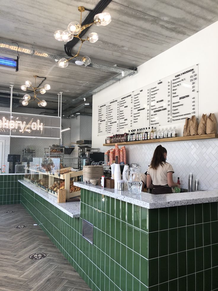 a woman is sitting at the counter in a restaurant with green tiles on the walls