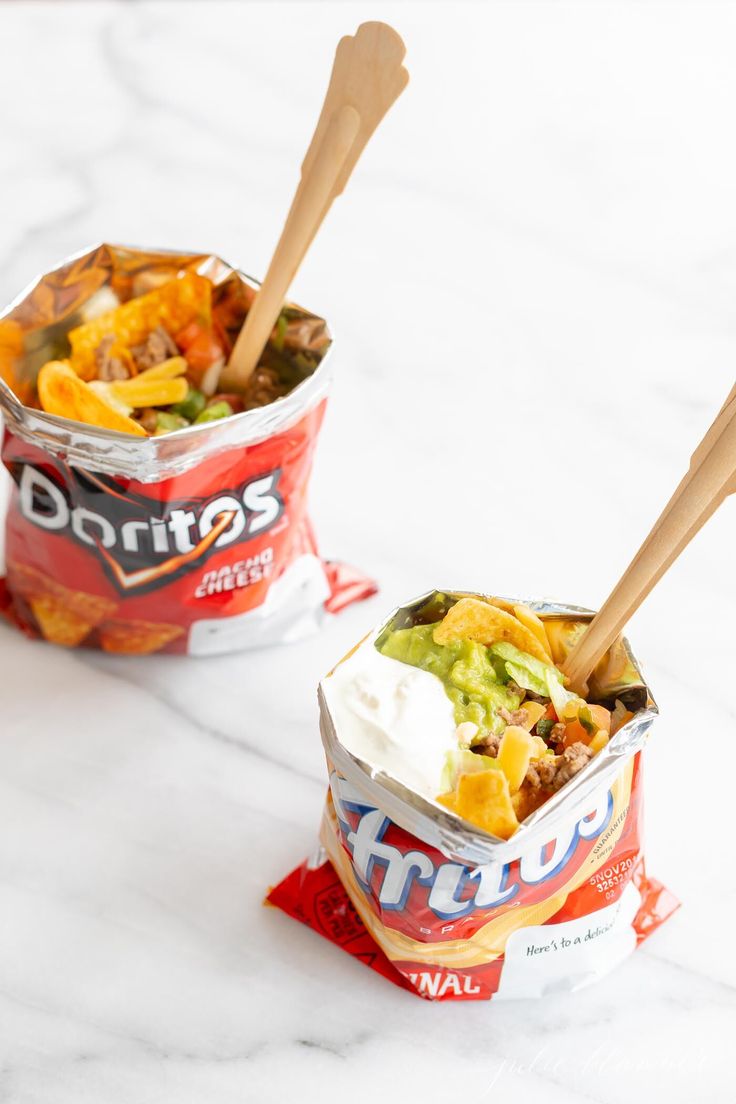 two bowls filled with food sitting on top of a white marble counter topped with wooden spoons