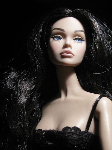 a close up of a doll with long black hair and blue eyes wearing a bra