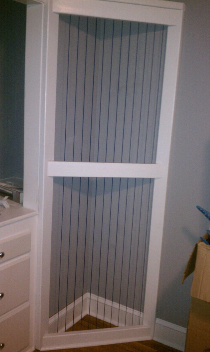 a corner closet in the corner of a room with white drawers and striped blinds on it