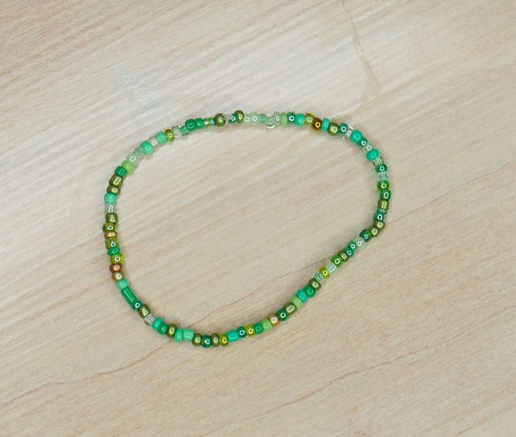 a green beaded necklace sitting on top of a wooden table