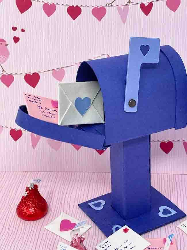 a blue mailbox sitting on top of a table next to some cards and hearts