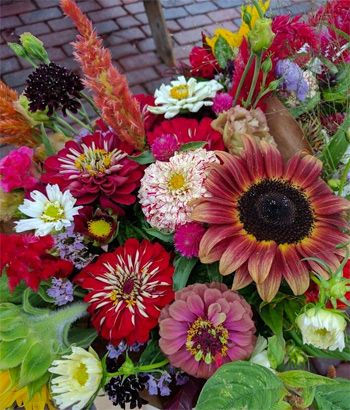 a bunch of flowers that are sitting on a wooden table with bricks in the background