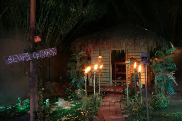 candles are lit in front of a small hut with tiki huts on the sides