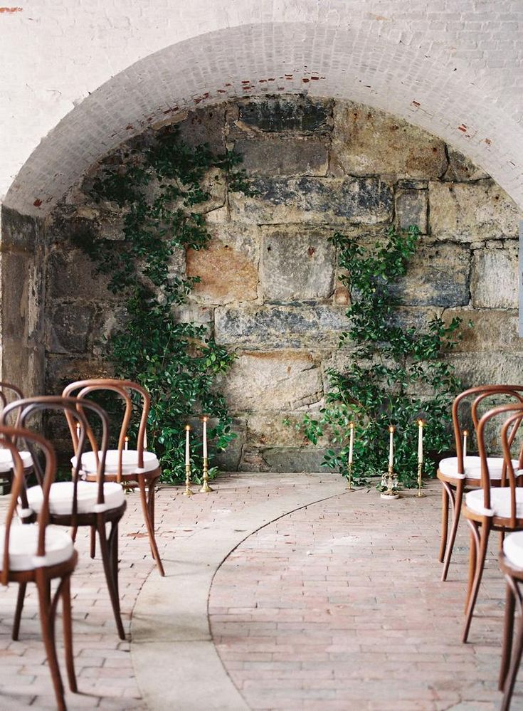 there are many chairs and tables set up in front of an archway with ivy growing on it