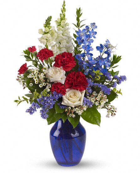 a blue vase filled with red, white and blue flowers