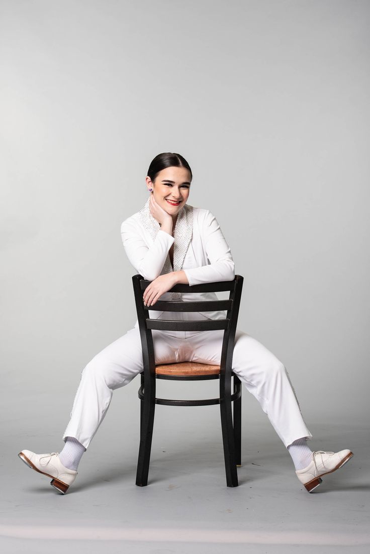 a woman sitting on top of a wooden chair with her arms crossed and legs crossed