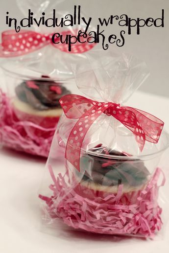 two cupcakes wrapped in cellophane with pink bows