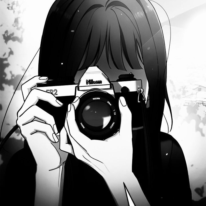 a person taking a photo with a camera in front of their face and the background is black and white