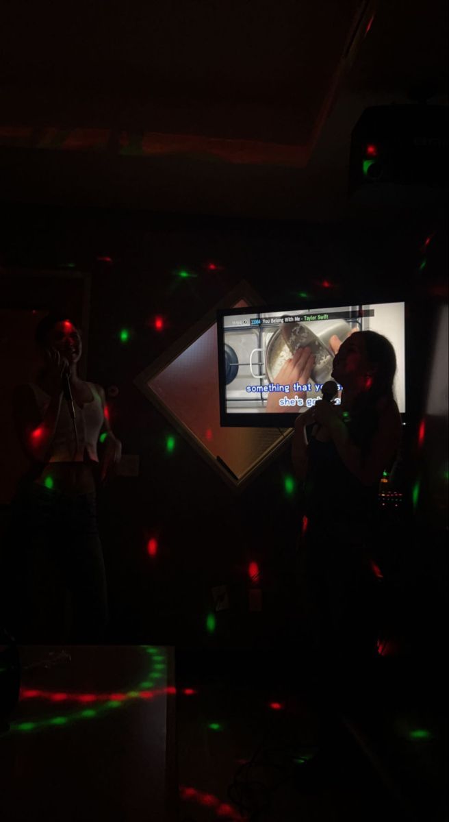 two people standing in front of a tv with green and red lights