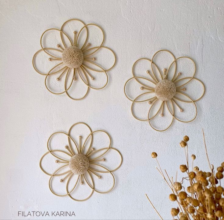 three metal flower wall hangings on a white wall