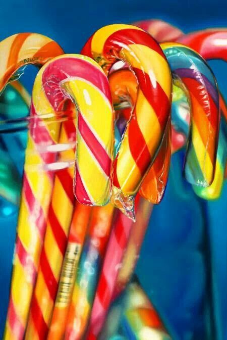 there are many candy canes in the glass vase on the table and blue background