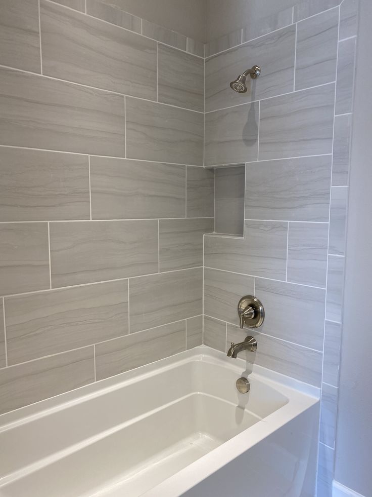 a white bath tub sitting inside of a bathroom next to a shower head and faucet