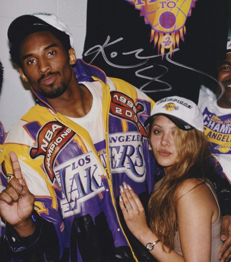 two people standing next to each other in front of a wall with autographs on it