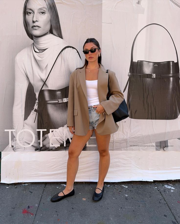 a woman standing in front of a wall with a handbag and purse on it