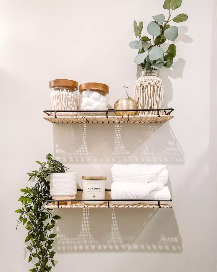 two shelves with towels, candles and other items on them next to a potted plant