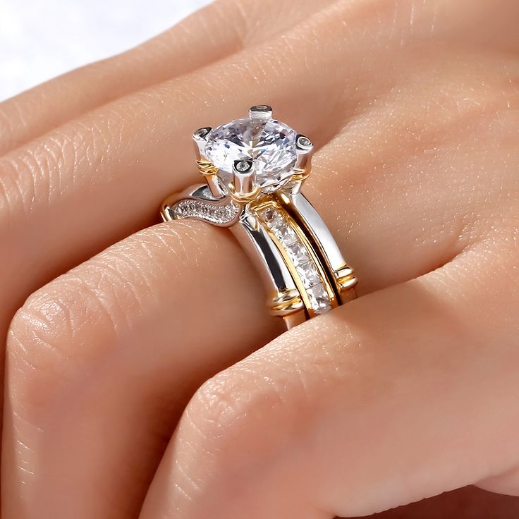 a woman's hand with two gold and white rings on top of her finger