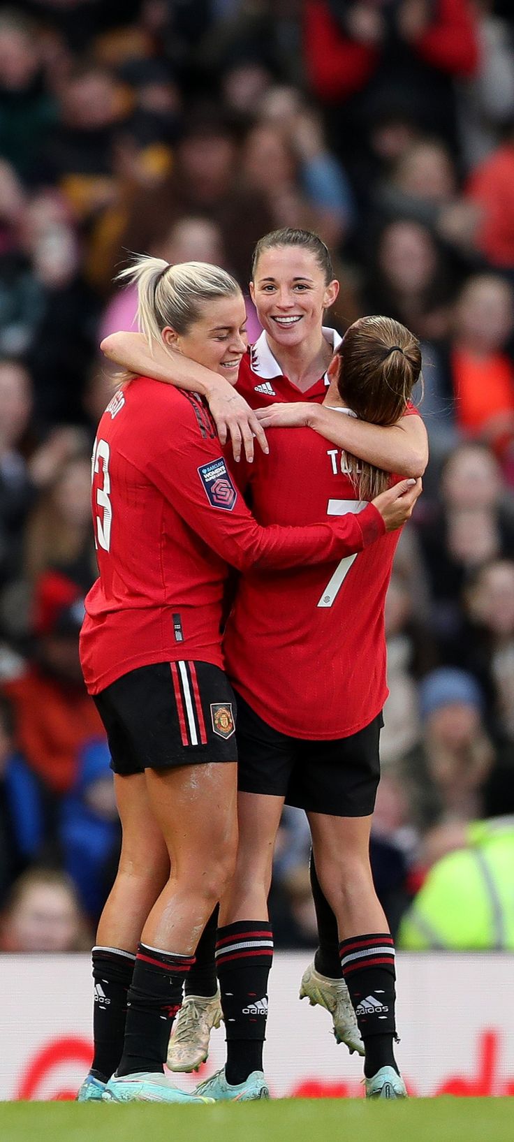 two female soccer players hugging each other on the field