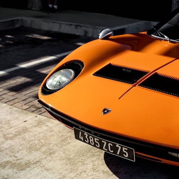 an orange sports car is parked on the street