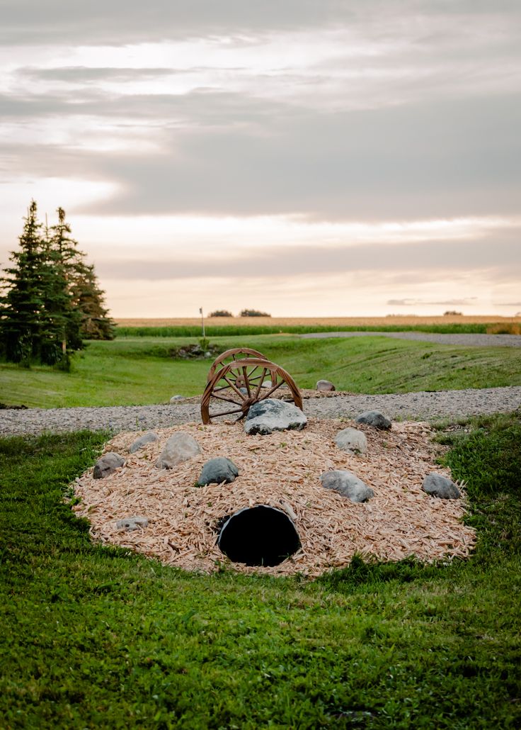 an open hole in the ground with rocks and grass