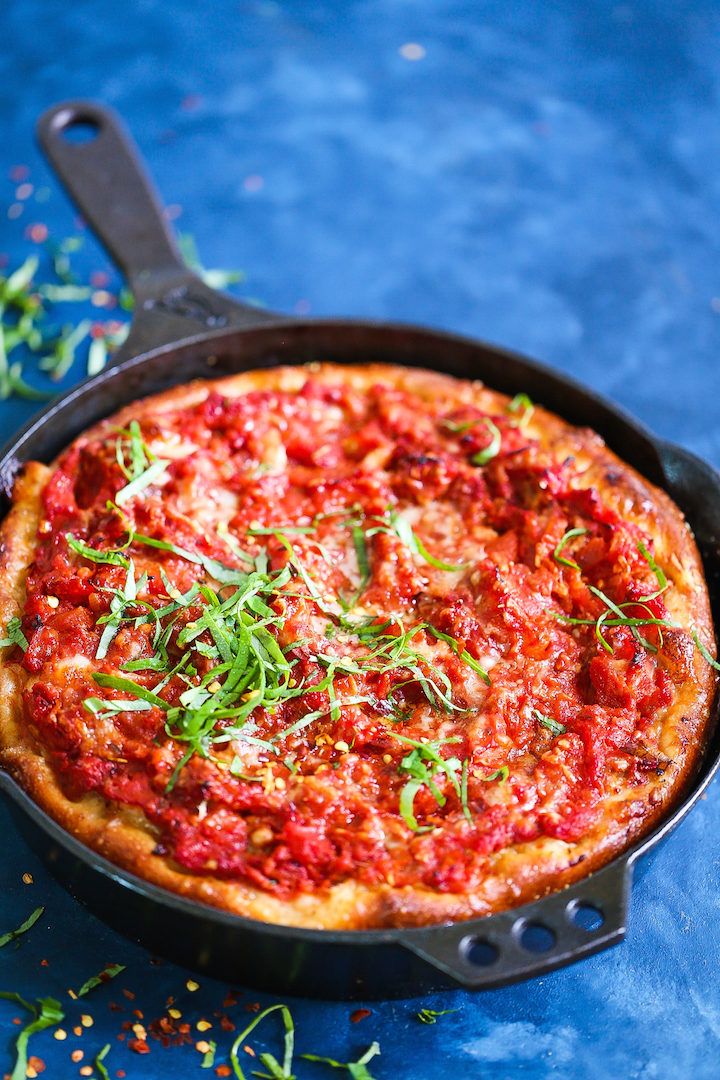 a deep dish pizza in a cast iron skillet on a blue surface with sprinkles