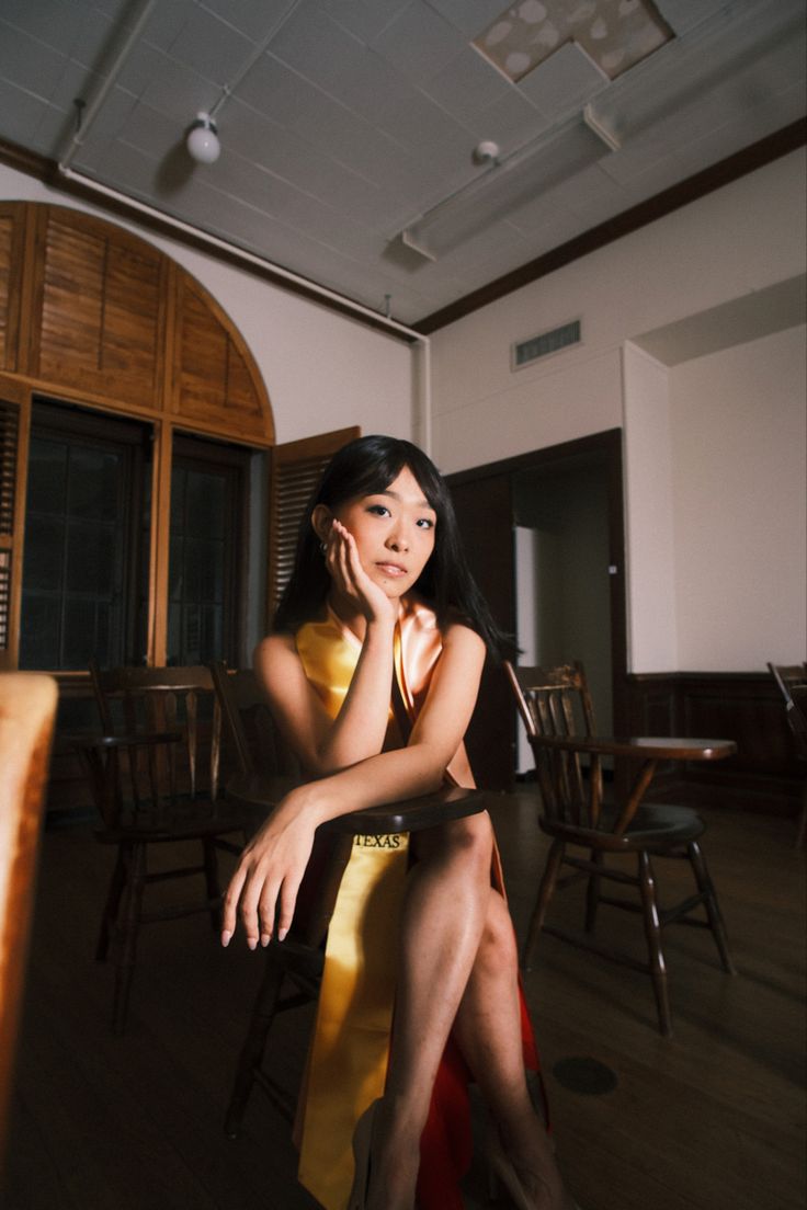 a woman sitting on top of a chair next to a wooden table in a room