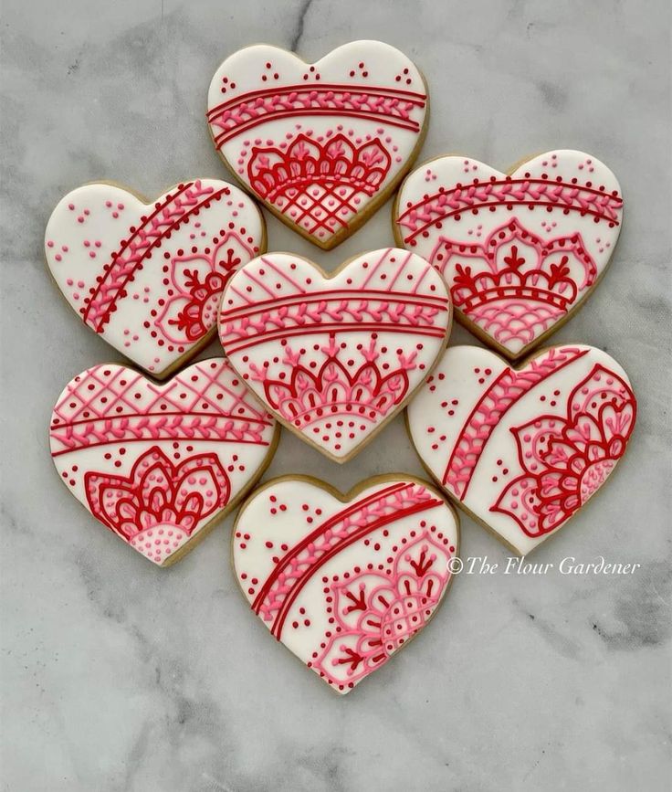 heart shaped cookies decorated with red and white icing on a marble countertop top