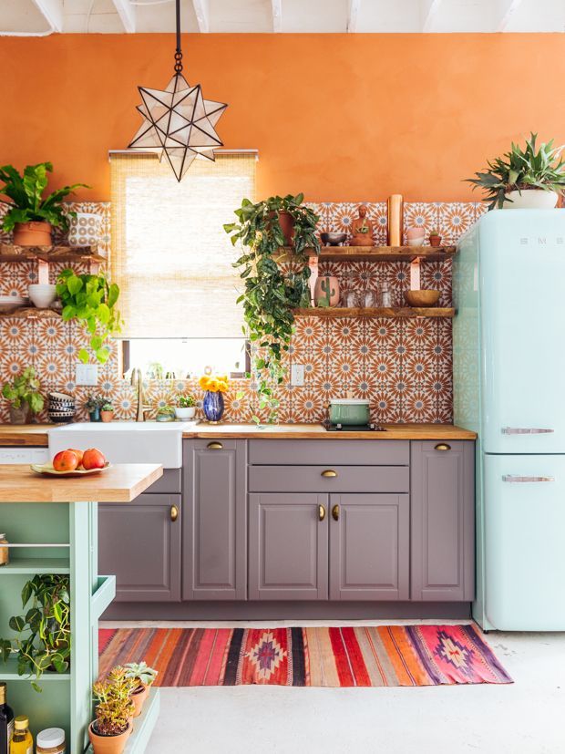 a kitchen with an orange wall and blue refrigerator freezer next to a green island