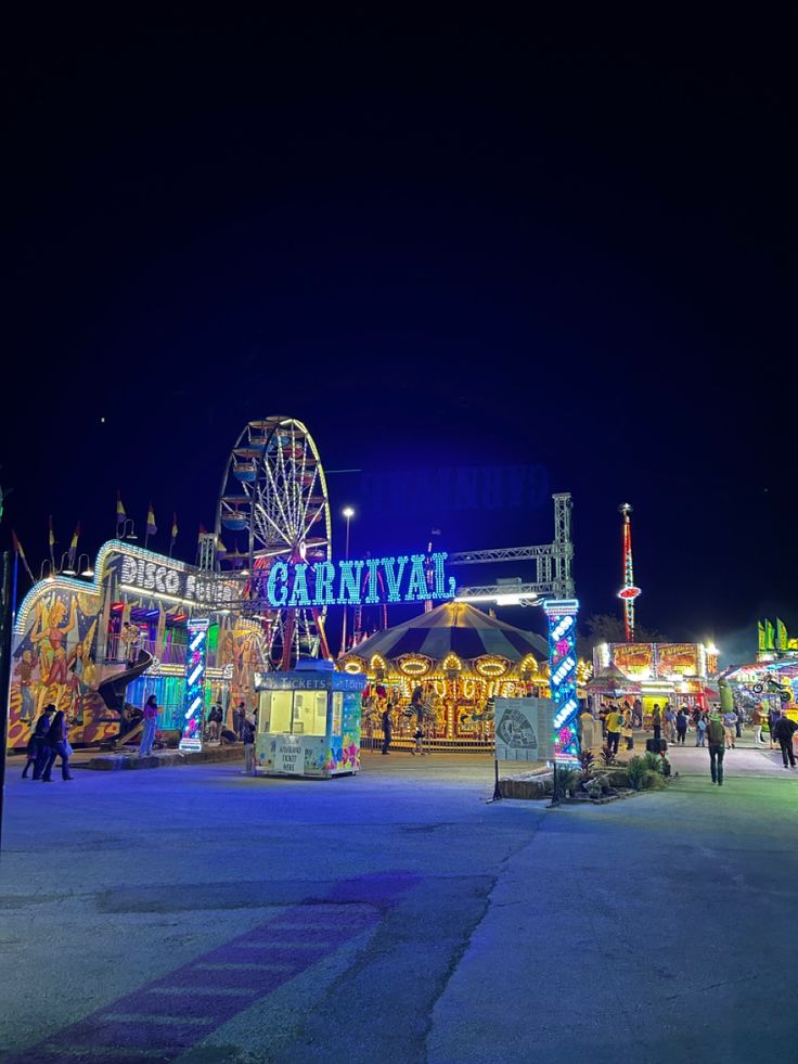 an amusement park at night with people walking around