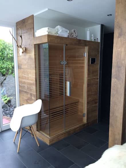 a bathroom with a walk in shower next to a white chair