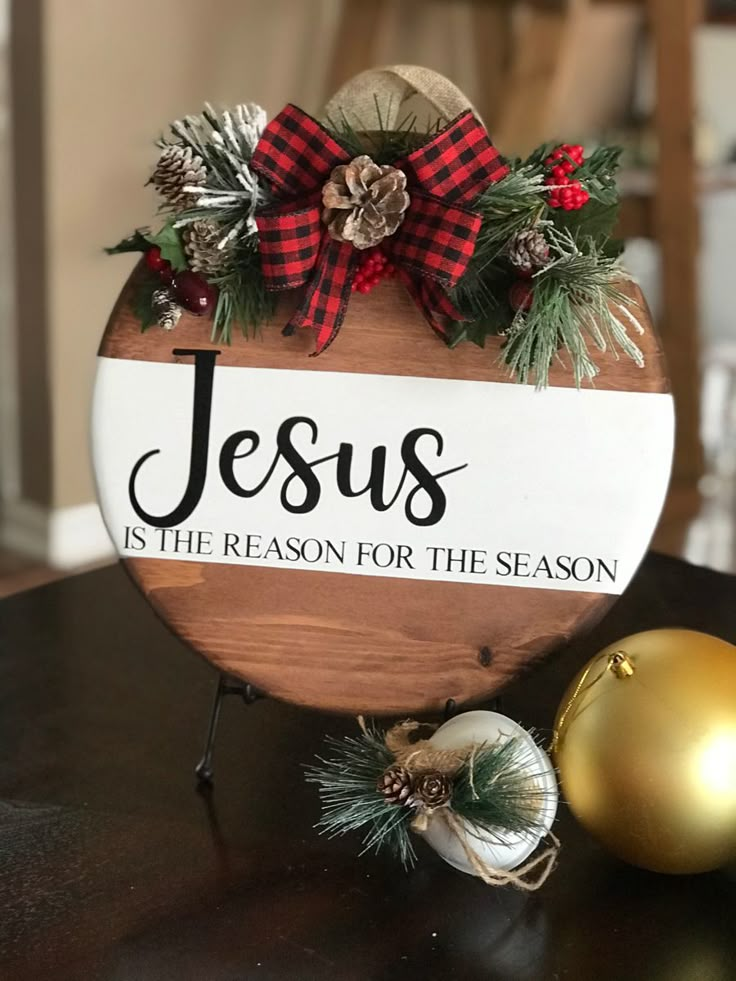 a wooden sign that says jesus is the reason for the season with ornaments around it