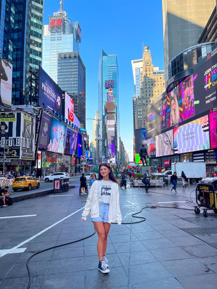 a woman is walking down the street in times square, new york city on a sunny day