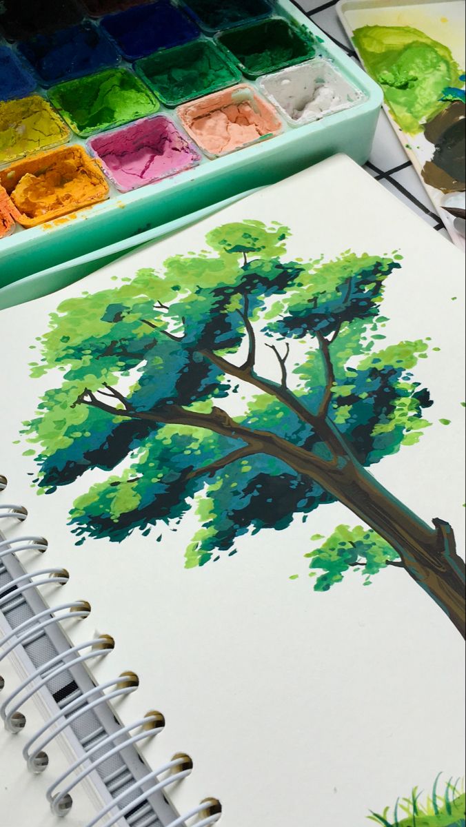 an artist's notebook with watercolor paints and a tree