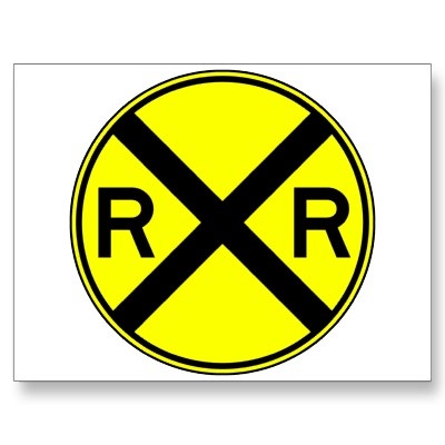 a round railroad crossing sign with the letter r in black on a yellow sticker