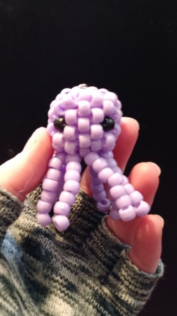 someone is holding a small beaded object in their left hand and it looks like an octopus