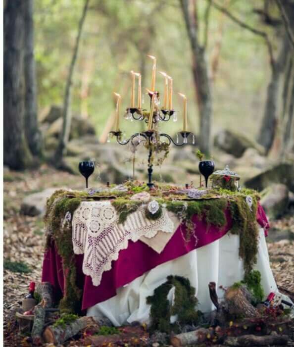 an image of a table with candles in the middle and moss growing on it, surrounded by trees