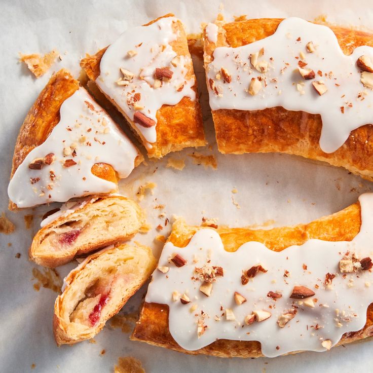 a pastry with white icing and nuts on it is cut into eight pieces to show the inside