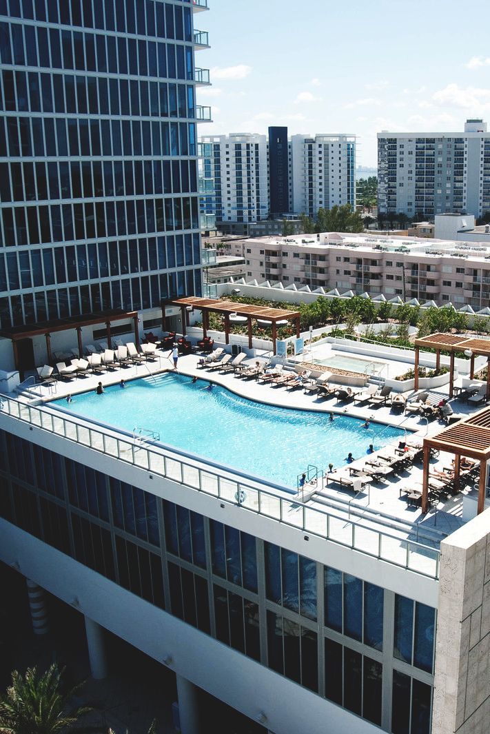 an aerial view of a swimming pool in the middle of a city with tall buildings