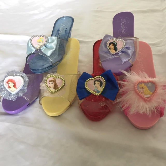 several princess shoes are laying on a bed