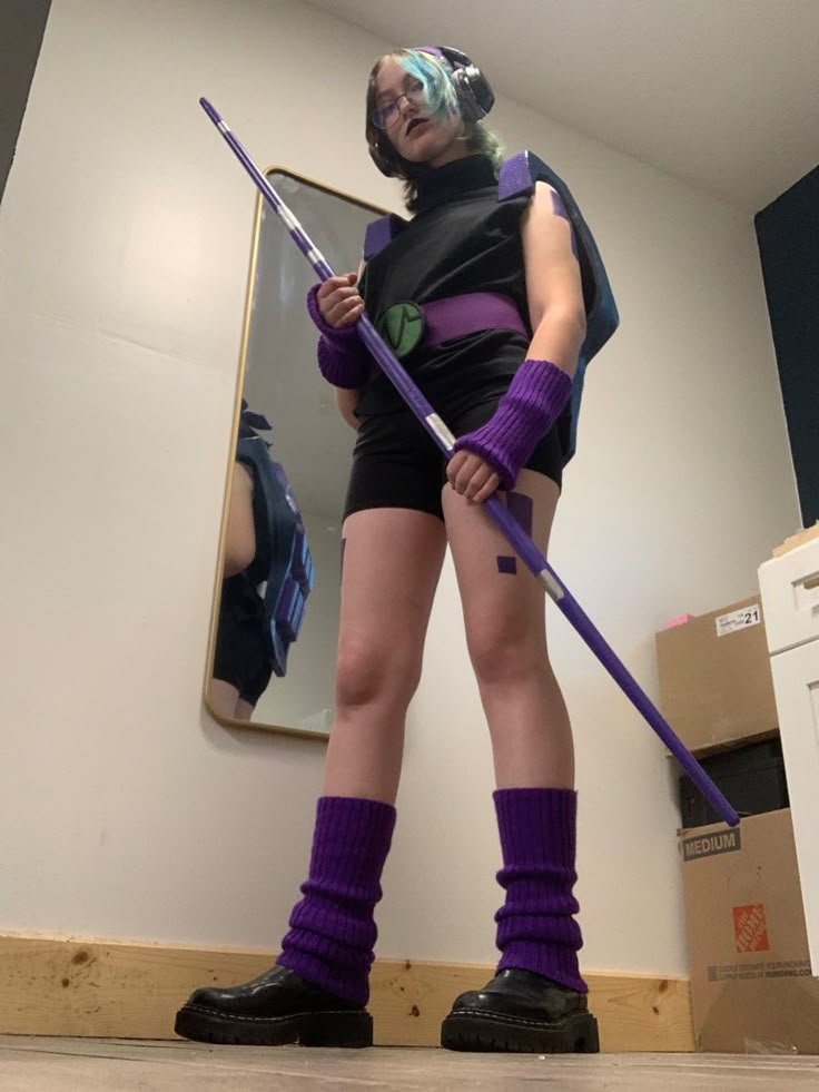 a woman dressed in purple and black is holding a broom while standing on the floor