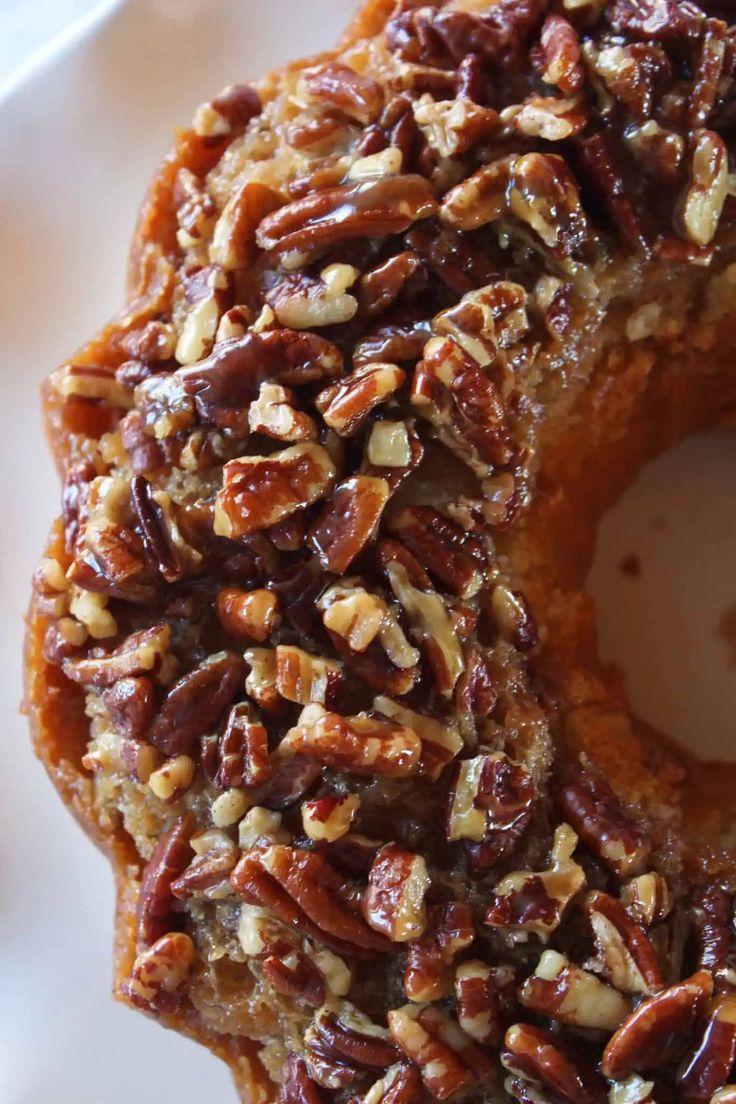 a close up of a doughnut on a plate with pecans and nuts around it