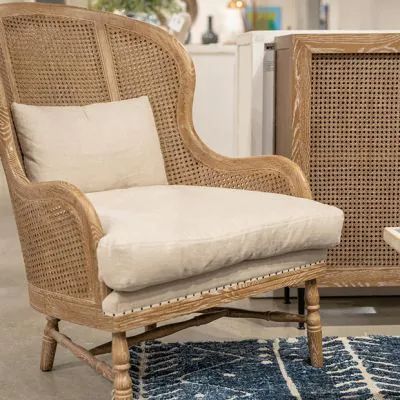 a wicker chair sitting on top of a blue rug next to a white table