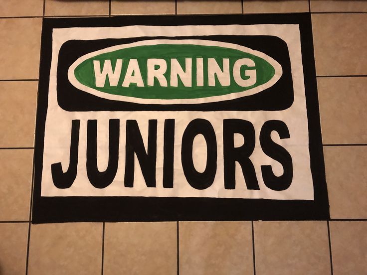 a black and white sign that says warning juniors next to a tiled floor in a bathroom