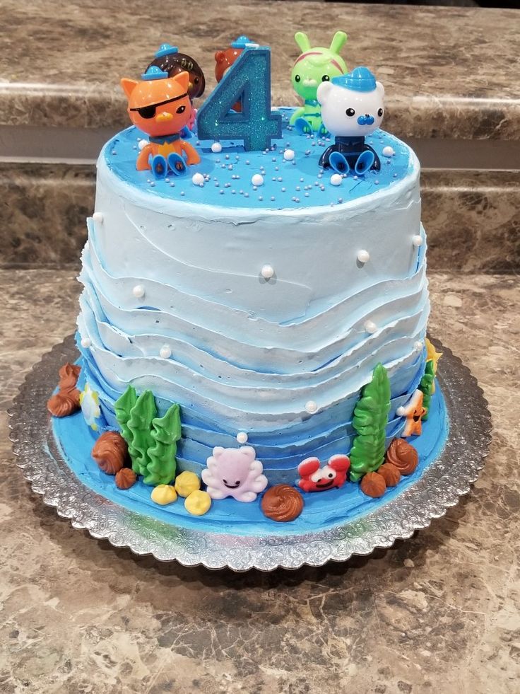 a blue and white birthday cake with an animal theme on the top is sitting on a marble countertop