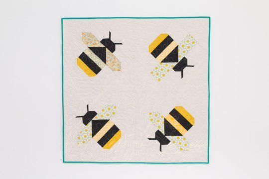 a quilted wall hanging with four bees on it