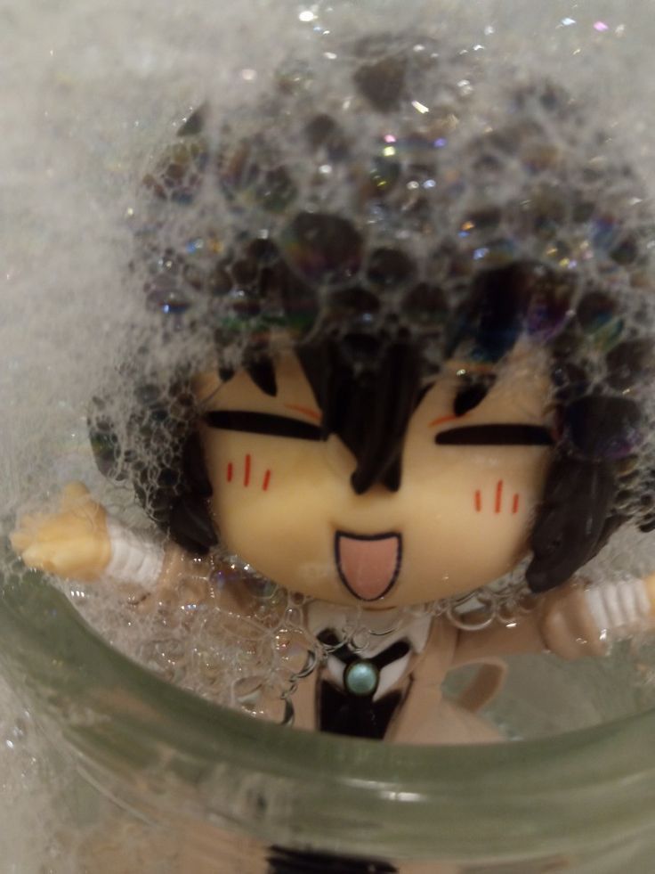 a toy doll is in the water with bubbles on it's head and eyes