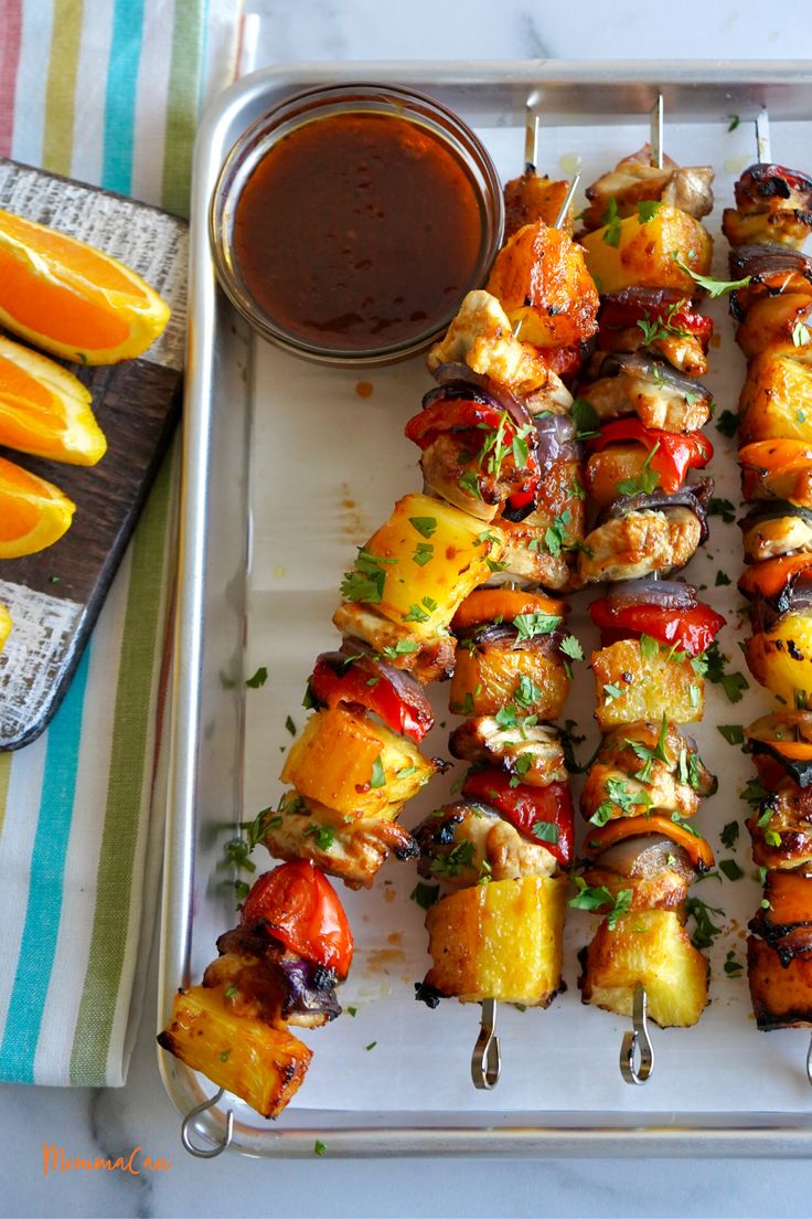 several skewers of food on a tray with sauce